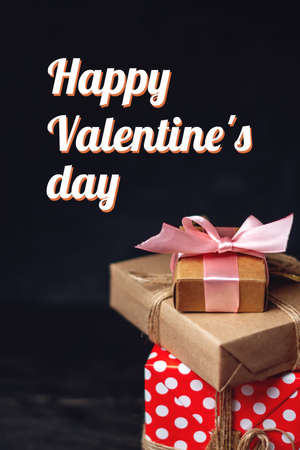 Holiday gift boxes Packed in crafting paper and red polka dots on dark wooden background. Vertical card Happy Valentine's day with textの写真素材