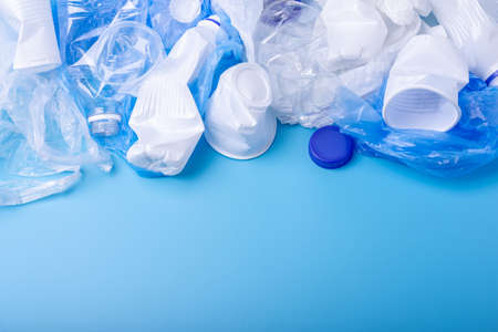 Used clean plastic garbage in a pile. Bottles and bags on blue background. The concept of waste sortingの写真素材