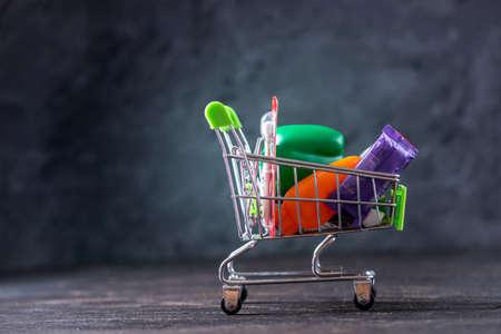 Daily purchases in the shopping cart on a dark background. Concept of shopping in stores and supermarketsの写真素材