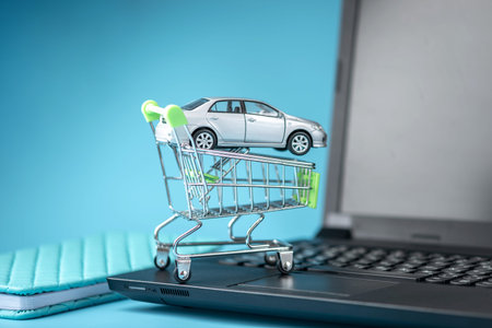 Shopping basket with car on laptop keyboard on blue background. The concept of online shopping...