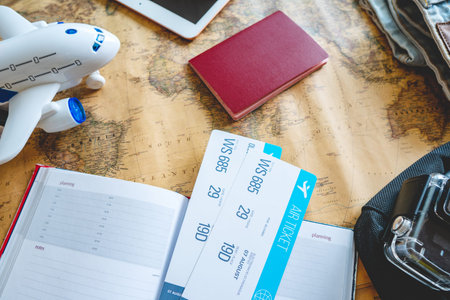 Airline tickets, passport, camera, tablet, jeans, plane and map on the table. The view from the top....