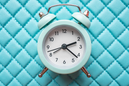 Blue analog metal alarm clock on stylish blue-pink background. The concept of time in pastel colors