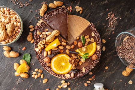 Chocolate cake with orange, cacao, mint leaves, peanuts and nuts. Top view. Concept healthy raw gluten-free and milk-and flour-free desserts for vegan foodの写真素材