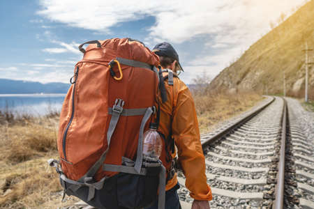 Tourist Hiking with an orange backpack is on the old railway at the foot of the mountain. Travel to lake Baikal, Russiaの写真素材