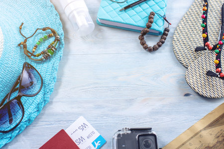 Travel holiday supplies: hat, sunglasses, flip flops, camera, passport and airline tickets on blue background. The concept of going on a trip to the sea on vacation. Top view. Flat layの写真素材