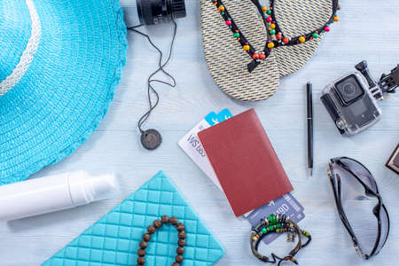 Travel holiday supplies: hat, sunglasses, flip flops, camera, passport and airline tickets on blue background. Concept of going on a trip to the sea on vacation. Top view. Flat layの写真素材