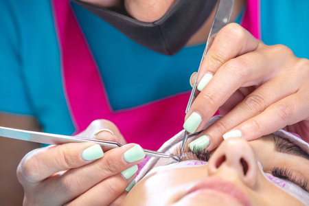 Woman master in the beauty salon work on eyelash extension to the client. Process of working as a...