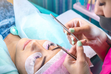 Woman master in the beauty salon work on eyelash extension to the client. Concept of profession in...
