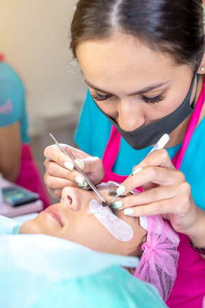 Woman master in the beauty salon work on eyelash extension to the client. Process of working as a...