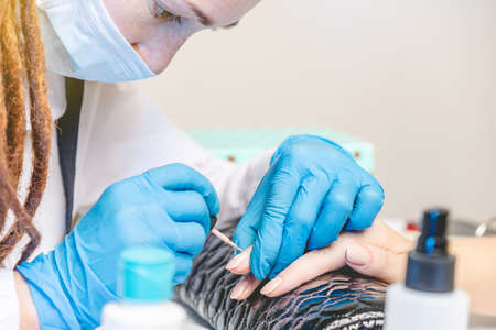 Woman manicure master makes gel coating varnish in the salon. The concept of beauty professional nail careの写真素材