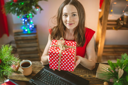 A beautiful woman holding a gift red box presented on Christmas eve for the New year. Emotional of...