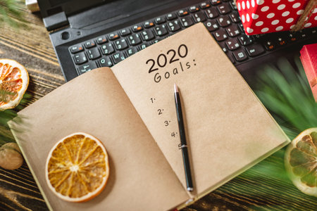 Notepad with open pages and pen on wooden background. Planning goals for the new year on Christmas...