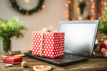 Gift red box with white polka dots on the laptop. Purchase discounts for Christmas in online stores...