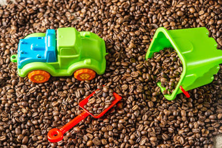 Children's bright toys a bucket with a shovel and a car on a pile of roasted coffee beans like in a...