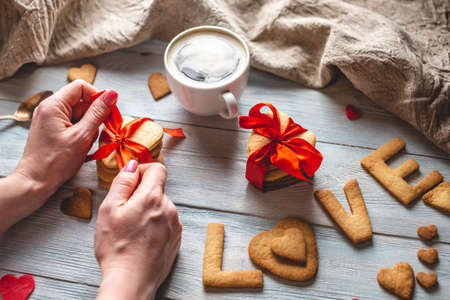 Cup of coffee and a message from a sweet cookie in the form of the word love on a blue wooden background. Romantic Valentine's day giftの写真素材