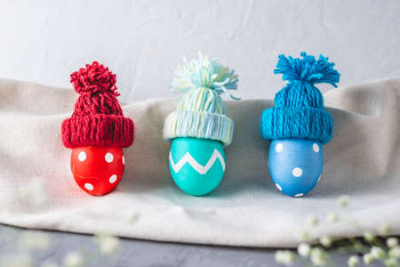 Bright colorful Easter eggs in a knitted winter hats on a gray background. Festive spring Easter card.の写真素材