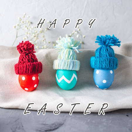 Bright colorful Easter eggs in a knitted winter hats on a gray background. Festive spring Easter card.の写真素材
