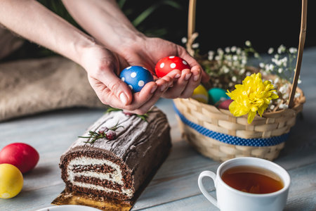 Festive Easter lunch with colorful bright eggs in a basket and an Easter cake on a wooden table. Concept of a traditional spring holiday.の写真素材