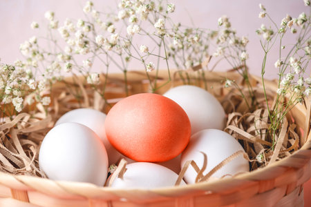 Bright red Easter egg among white ones in a basket on a light background. Festive spring greeting...