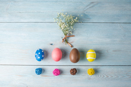 Bright colorful Easter eggs with spring flowers on a blue wooden background. Festive spring Easter...