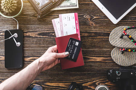 All the necessary things for the flight on vacation. Plane tickets, passport, phone and credit card on a wooden background. The concept of easy preparation for travel. Top viewの写真素材