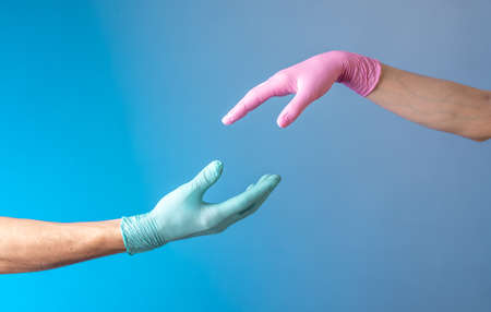 Two hands in rubber medical gloves. Romantic relationships between people. Protection, isolation and distance during the Covid-19 coronavirus pandemic.の写真素材