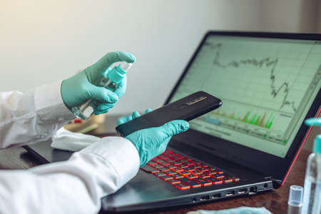 Women's hands in sterile gloves handles their workplace wiping a napkin with a disinfectant laptop. Cleanliness and hygiene in the fight against virusesの写真素材