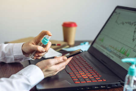 A woman applying a disinfectant to her hands before working at the computer in the office. Cleanliness and hygiene in the fight against virusesの写真素材