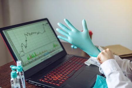 A woman putting on a pair of rubber mint gloves before working at a computer in the office....