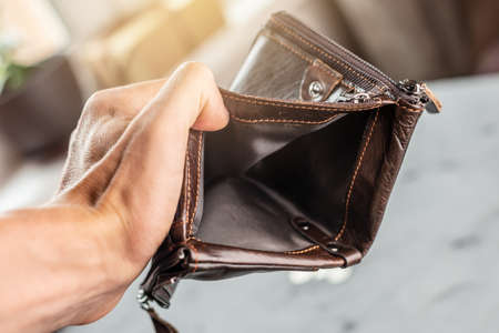 The man is holding an open empty brown leather wallet purse. The concept of economic crisis and business bankruptcy in the post-pandemic periodの写真素材