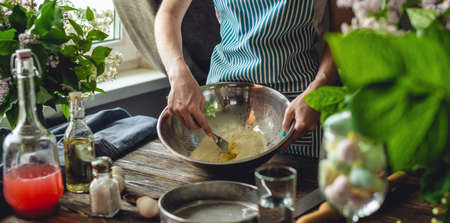 A woman is preparing fresh dough in a cozy atmosphere. Concept of cooking tasty dough dishes at home.の写真素材