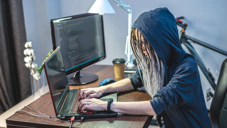 Woman hacker in a hood are programming virus code on a laptop. The concept of Internet fraud and personal data hackingの写真素材