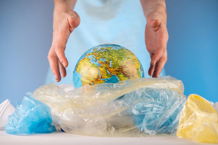 A woman is pulling out an Earth in form globe of a pile of plastic garbage. Concept of environmental...