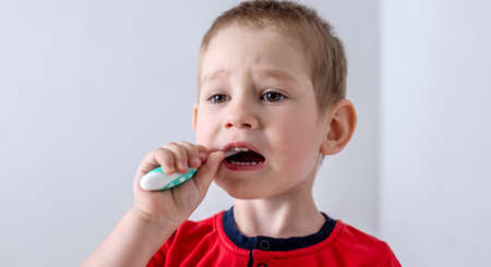 A little boy is learning to brush his teeth using a toothbrush. Concept of child hygiene and independence.の写真素材
