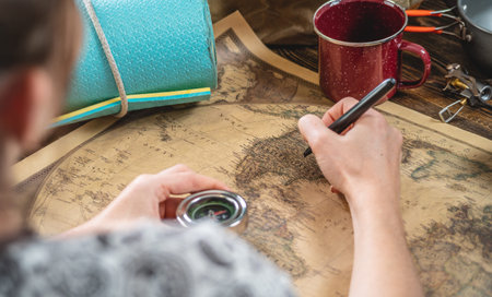 A woman is choosing a place for her next trip by pointing to a map of the world on a wooden table...