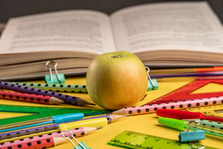 Apple, book and colorful school stationery items on a yellow background. Back to school conceptの写真素材