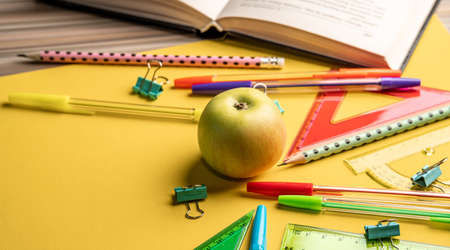 Apple, book and colorful school stationery items on a yellow background. Back to school conceptの写真素材