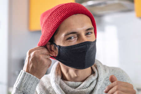 Young man is putting on a black protective face mask. Concept of prevention, care for yourself and others people.の写真素材
