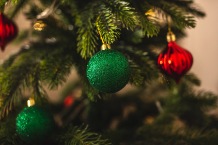 Beautiful Christmas tree with green toy on branches close up. Concept of a New year atmosphere and festive mood.の写真素材