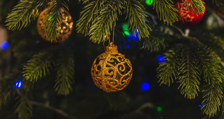Beautiful Christmas tree with gold toy on branches close up. Concept of a New year atmosphere and...