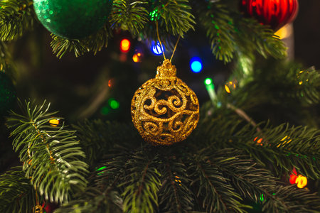 Beautiful Christmas tree with gold toy on branches close up. Concept of a New year atmosphere and festive mood.の写真素材