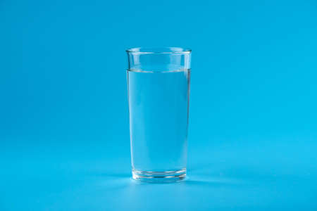Clean fresh water in a glass on a blue backgroundの写真素材