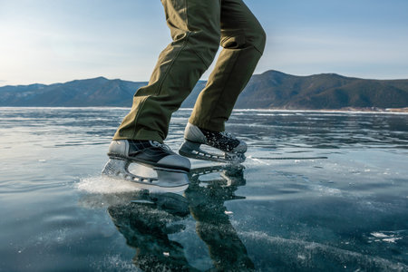 Feet in skates on the beautiful blue cracked ice of a frozen lake. Top viewの写真素材
