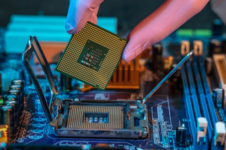 The engineer's gloved hand is holding the CPU chip against the background of the motherboard....