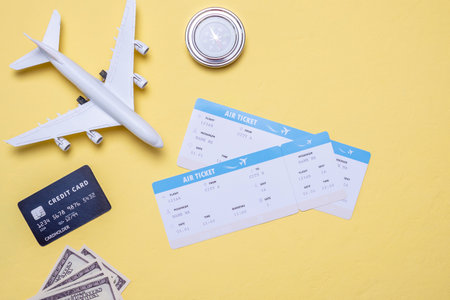 Plane, airline tickets, money and compass on a yellow background. Concept of booking tickets and air travel. Top view.の写真素材