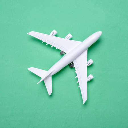 Miniature of an airplane on a green background with a copy space, top view. Concept of travel, vacation and business trip.の写真素材