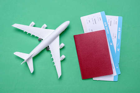 Miniature of the plane, airline tickets and passport on a green background. Travel, vacation and ticket booking concept.の写真素材