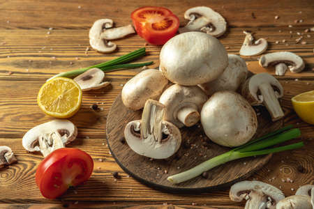 Mushrooms, vegetables, lemon and spices on a wooden table. Concept of ingredients for cooking a delicious dish.の写真素材
