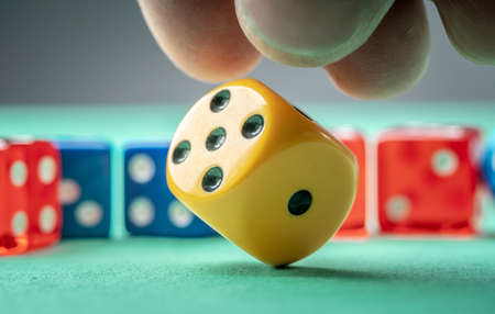 The hand is throwing yellow dice on the green table. The concept of a casino and a lucky chance to winの写真素材