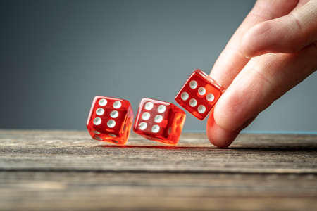The hand is throwing red dices on the wooden table. The concept of a casino and a lucky chance to winの写真素材